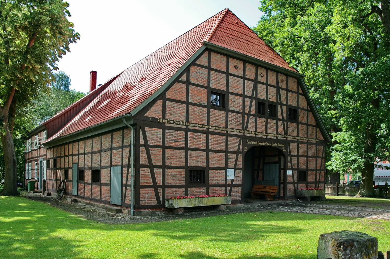 Bürgerhaus von 1861 in Müden (Aller), ein Fachwerkhaus mit rotem Ziegeldach zwischen alten Bäumen